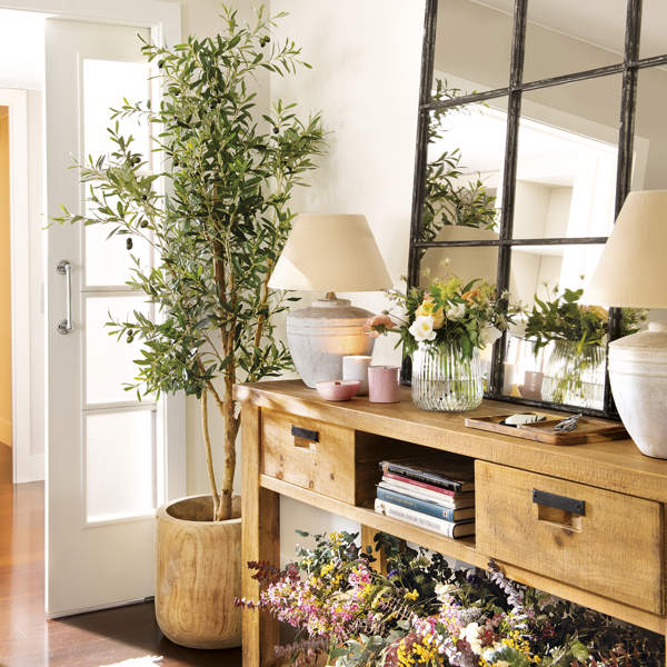 recibidor con mueble de madera rústica con espejo, olivo y flores secas, lámparas de mesa y jarrón de cristal